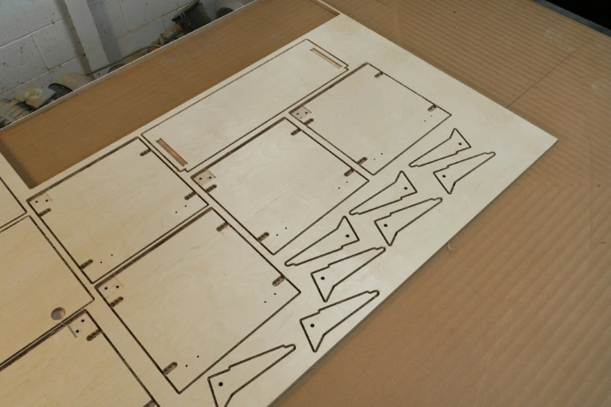 Laser-cut wooden pieces on a cardboard surface